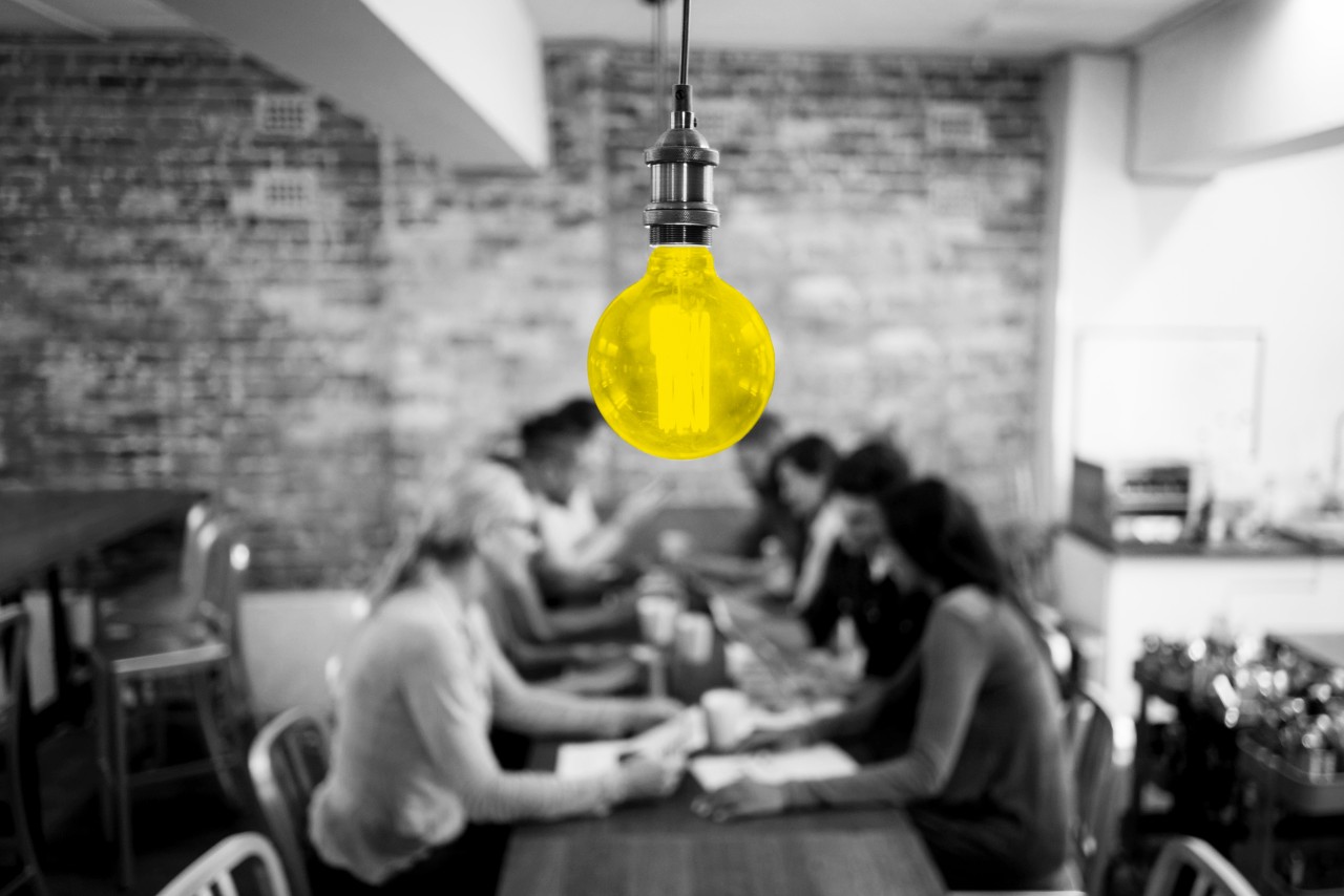 642980978 Group of business people brainstorming at a creative office and a light bulb in the foreground