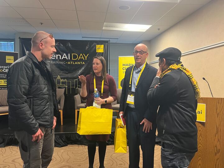 three men and a woman talking after the event holding yellow swag bags